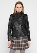 Schwarze Lederbikerjacke mit Reißverschlusstaschen und Schulterklappen, mit tailliertem Schnitt. Tragen über einem braunen Rollkragenpulli und einem karierten Rock.