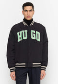Schwarze Bomberjacke mit weißen und hellgrünen „HUGO“-Buchstaben, gerippten gestreiften Bündchen und Saum sowie Druckknopfverschluss. Glatte Stofftextur.