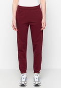 Burgunderfarbene Sweatpants aus Baumwollmix mit elastischem Bund, elastischen Bündchen und einem bedruckten Grafikdesign auf der Vorderseite. Kombiniert mit grauen Sneakers.