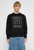 Junger Mann trägt einen schwarzen Diesel Industry Sweatshirt und blaue Cargo-Jeans, steht vor einem schlichten hellgrauen Hintergrund.