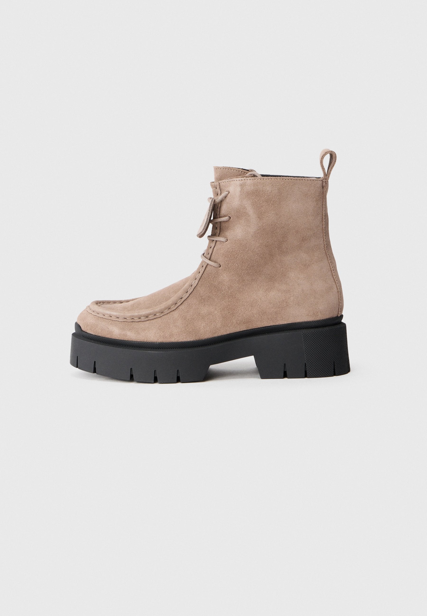 Beige Wildleder-Stiefelette mit runder Spitze, gesteppten Details, schwarzer robuster Sohle und einer Schlaufe hinten für einfaches Anziehen.