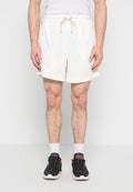 Mann trägt weiße Shorts mit Kordelzug, weiße Socken und schwarze Sportschuhe, steht vor einem einfarbigen weißen Hintergrund.