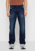 Blaue Jeans aus Denim mit geradem Bein, subtiler Ausbleichung, Fünf-Taschen-Design und silberner Knopfleiste, kombiniert mit einem braunen Hemd.