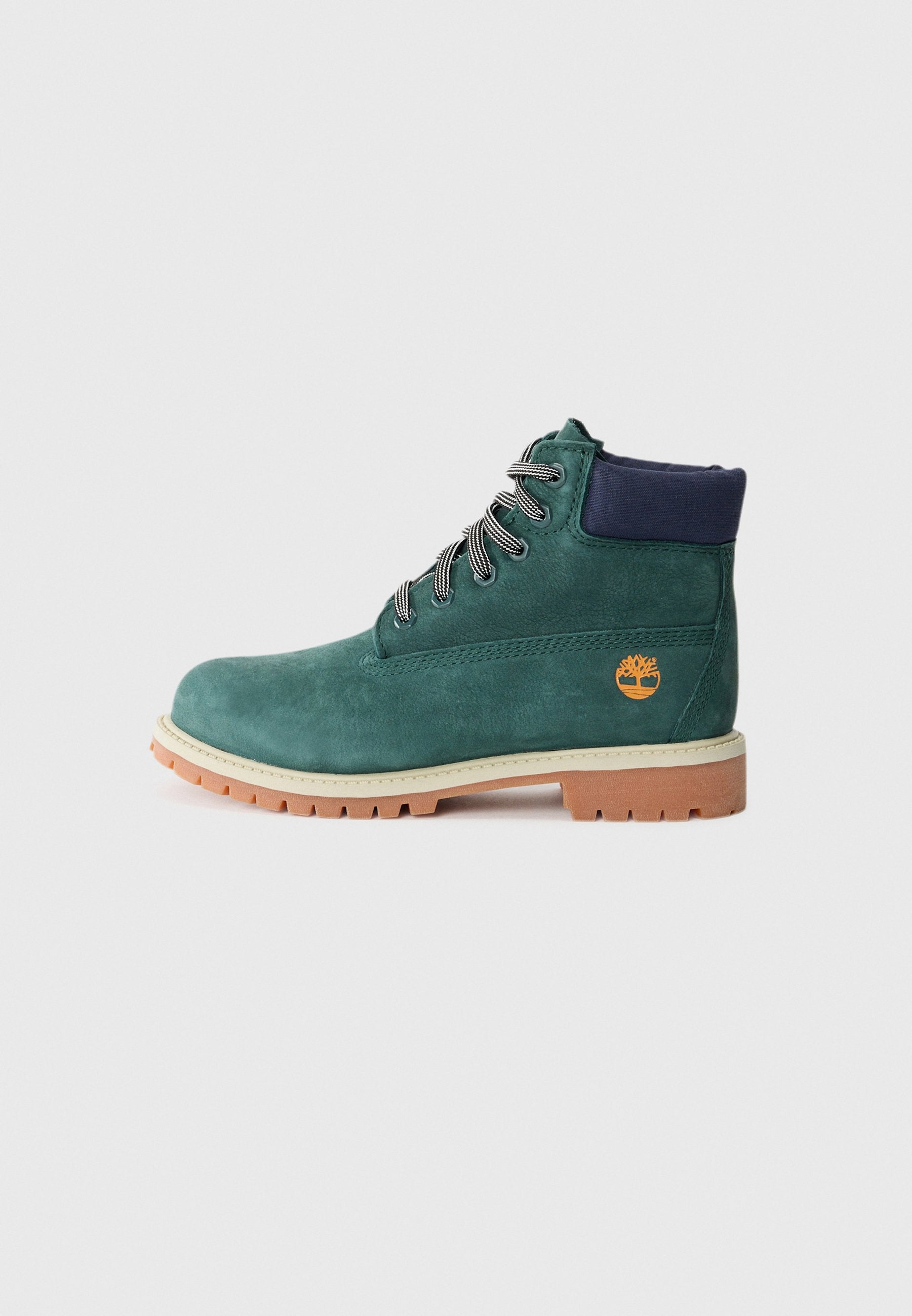Grüne Wildleder-Stiefeletten mit einem marineblauen Kragen, grauen Schnürsenkeln und einer braunen Gummisohle mit einem Baum-Logo an der Seite.