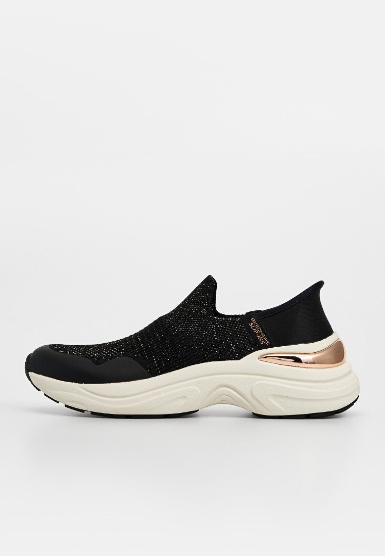 Schwarzer Slip-On-Sneaker mit gestricktem Obermaterial, weißer dicker Sohle und metallischem Roségold-Akzent an der Ferse, Seitenansicht vor einfachem Hintergrund.