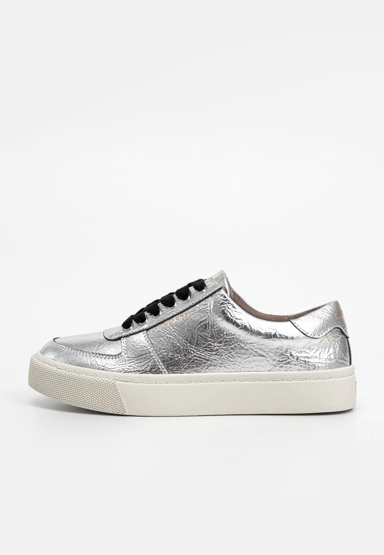 Silberne metallische Sneakers mit einer runden Spitze, strukturiertem Obermaterial, flacher weißer Sohle, schwarzen Schnürsenkeln und dezentem Branding an der Seite.