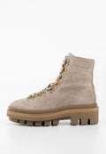 Beige Wildleder-Stiefelette mit dicker Profilsohle, metallenen Ösen und beigen Schnürsenkeln, geeignet für robuste Outdoor-Aktivitäten.