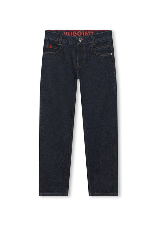 Dunkelblaue Denim-Jeans verfügen über einen geraden Schnitt, ein Fünf-Taschen-Design und kontrastierende Nähte. Der Bund zeigt ein rotes Logo-Label.