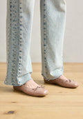 Helle rosa patentierte Ballerinas mit Schleifendetail, kombiniert mit hellblauen hochgeschnittenen Jeans mit ausgefransten Säumen und einem ausgewaschenen Denim-Look.