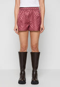 Rosa gestepptes Shorts mit einem Rautenmuster, elastischem Bund, kombiniert mit kniehohen braunen Lederstiefeln. Glatte Textur, lässiges Design.