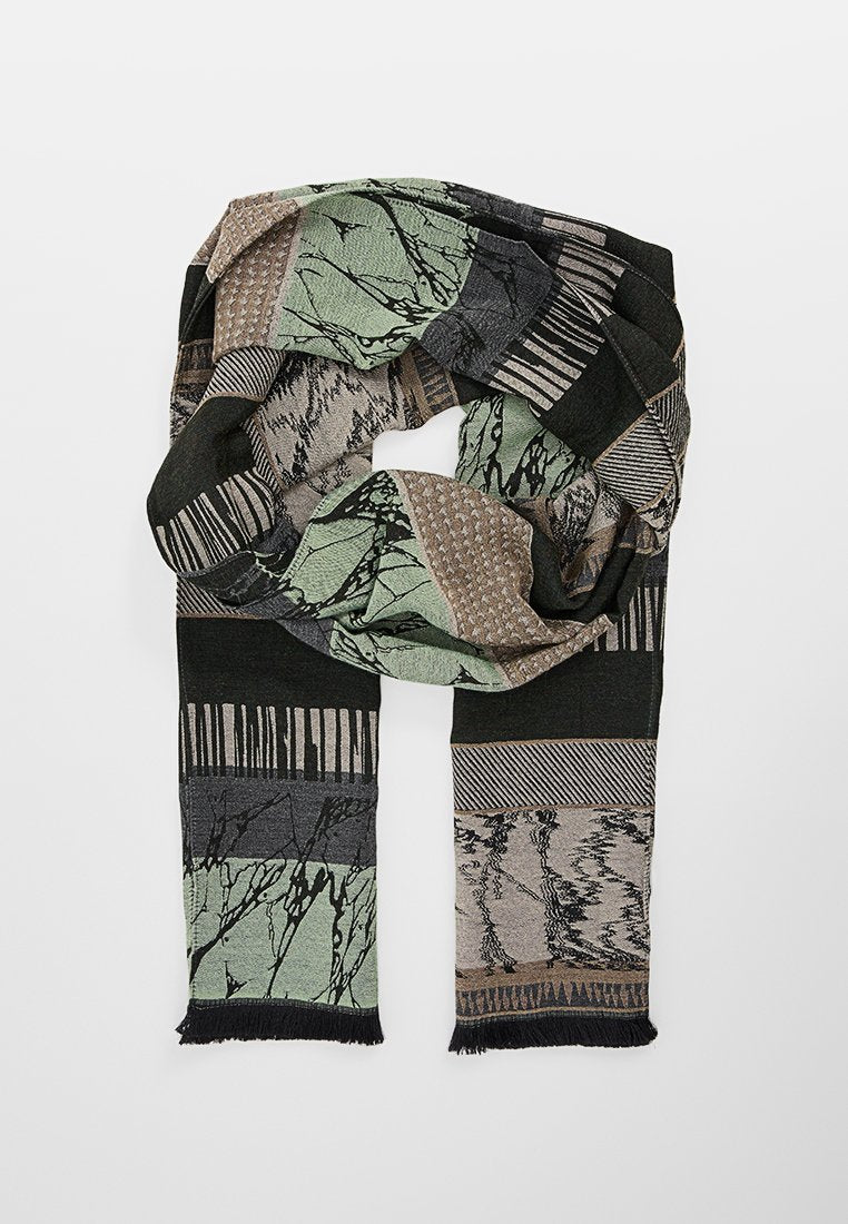 Texturiertes Tuch mit einem abstrakten Muster in verschiedenen Grüntönen, Schwarz und Beige, mit Fransenenden und geometrischen Designs.