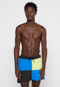 Herren-Badebermuda im Patchwork-Design mit blauen, grünen, schwarzen und gelben Paneelen. Hergestellt aus leichtem Stoff mit einem elastischen Bund.