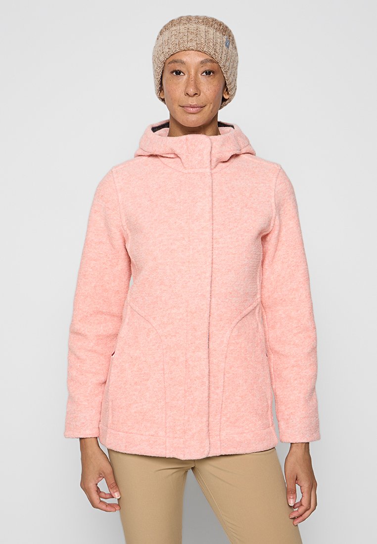Rosa Fleecejacke mit Stehkragen und Kapuze, ausgestattet mit Vordernähten und zwei seitlichen Taschen. Kombiniert mit einer beigen Strickmütze.