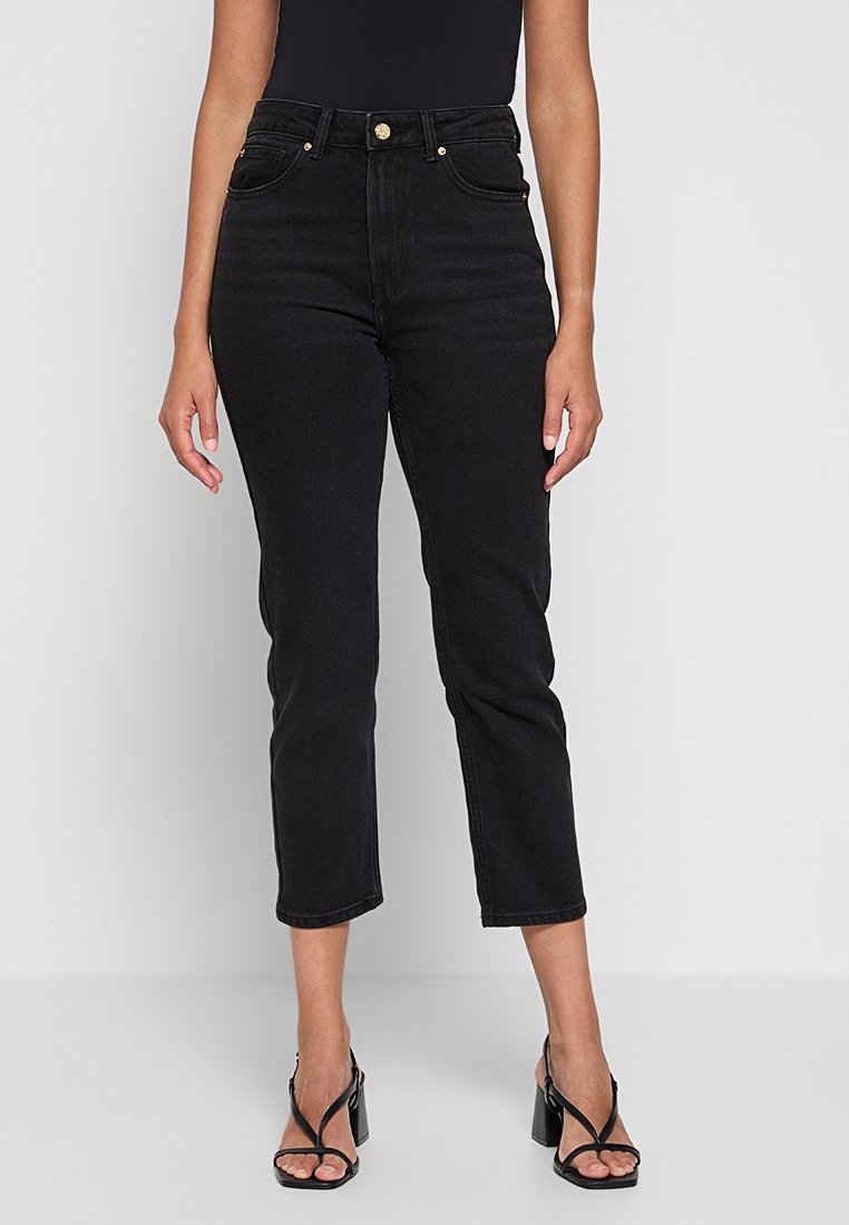 Schwarze Denim-Jeans mit hohem Bund, geradem Bein, fünf Taschen und Knopfdetails in Goldfarbe. Glatte Textur mit verkürzter Länge.