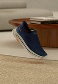 Marineblaue Slip-On-Sneaker mit Obermaterial aus Mesh für Atmungsaktivität, weißer Außenfläche mit orangefarbenen Akzenten und leichtem Design für Komfort.