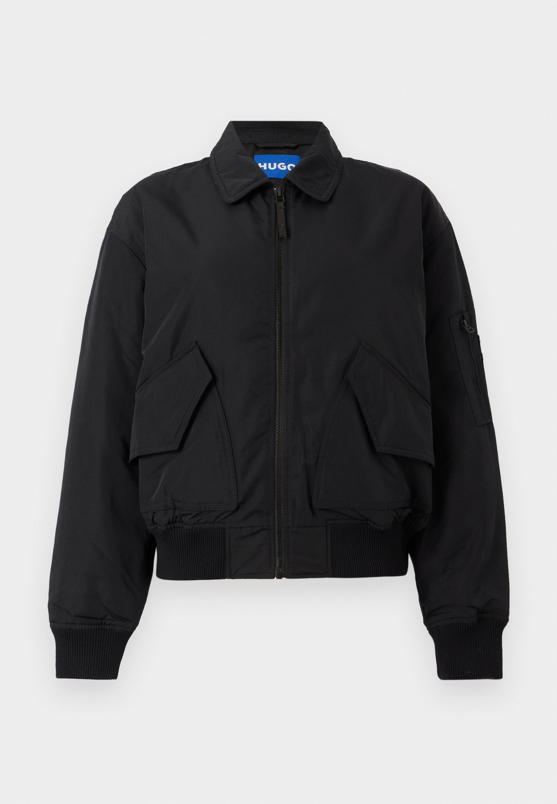 Schwarze Bomberjacke mit Reißverschluss, zwei großen Klappentaschen vorne, gerippten Bündchen und Saum sowie einer kleinen Reißverschlusstasche am linken Ärmel.