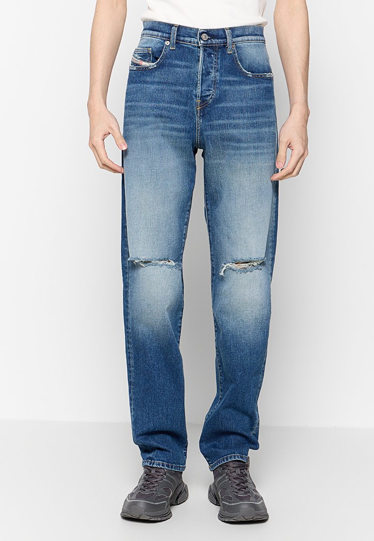 Hellblaue Jeans aus Denim mit geradem Bein, ausgestattet mit aufgerissenen Knien, fünf Taschen und einem Reißverschluss. Der Stoff zeigt dezente Verblasstheit.
