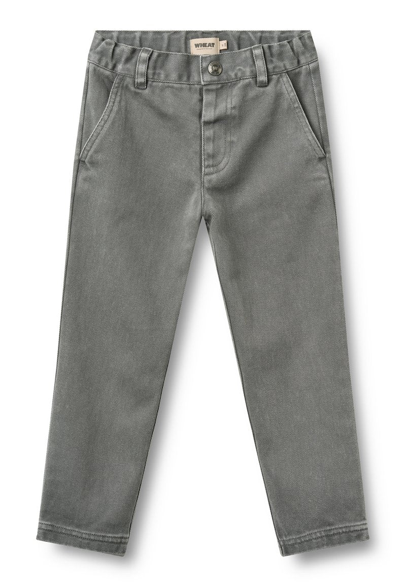 Graue Kinderhose mit Fronttaschen, Gürtelschlaufen, Knopfverschluss und einem Etikett mit der Aufschrift „Wheat“ an der Innenseite des Bunds.