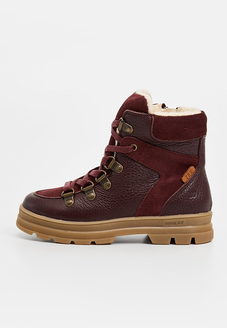Burgunderfarbene Wanderschuhe mit einem Obermaterial aus strukturiertem Leder und Wildleder, Futter aus Fell, metallischen Ösen und einer strapazierfähigen braunen Gummisohle.