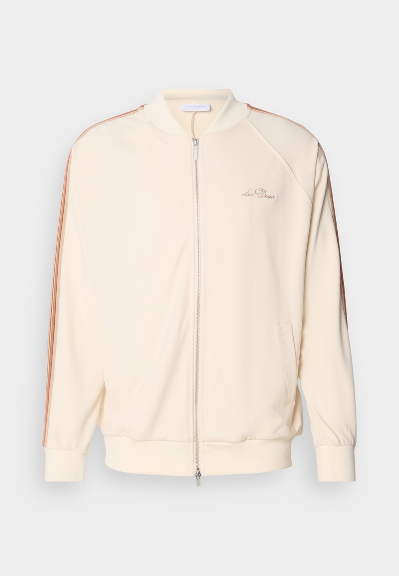Cremfarbene Bomberjacke mit Reißverschluss, kontrastierenden braunen Streifen auf den Schultern, gerippten Bündchen und dezentem Logo-Stick auf der Brust.
