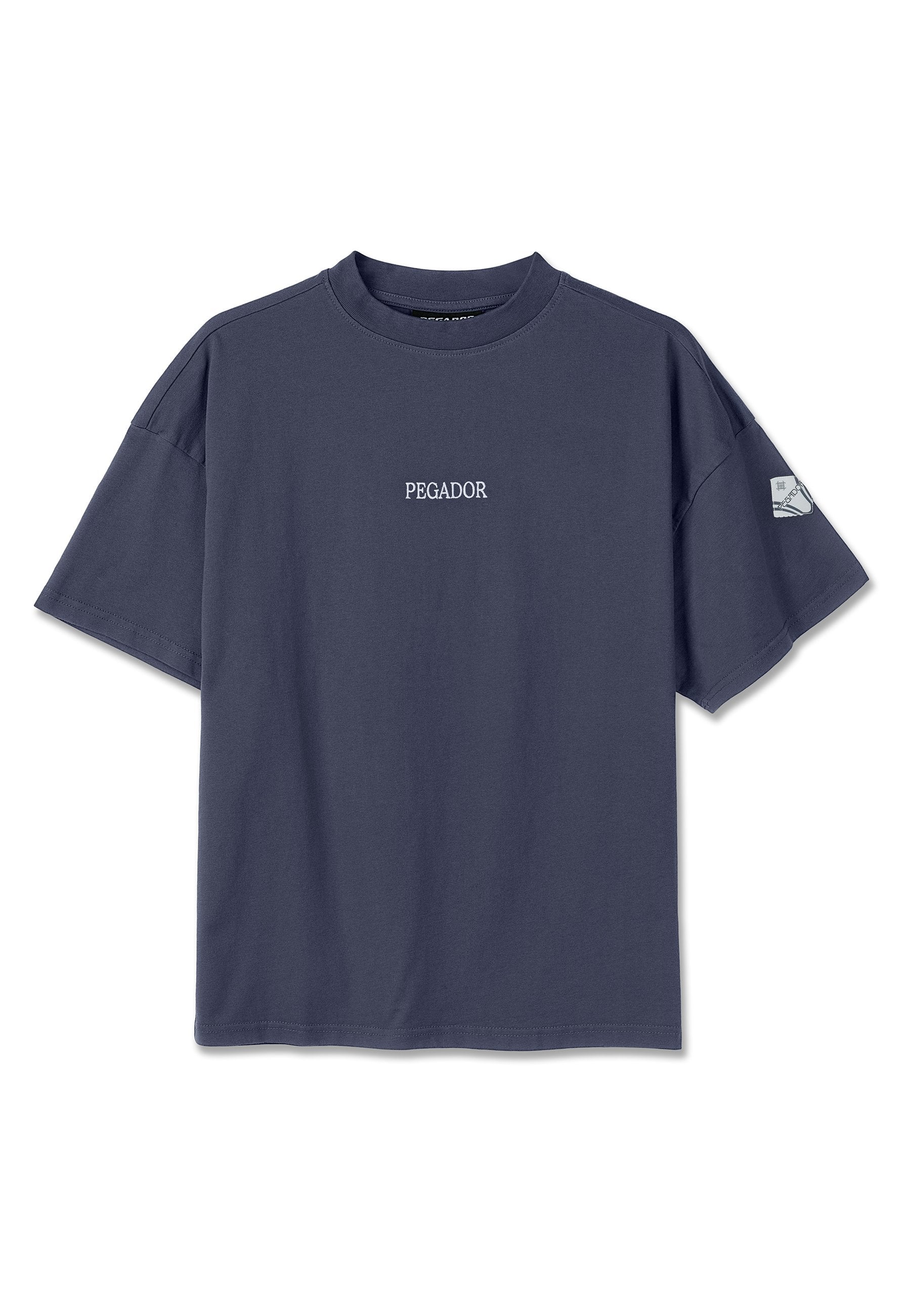 Marineblaues T-Shirt mit kurzen Ärmeln, auf der Brust mit dem Schriftzug "PEGADOR" und einem kleinen Aufnäher am linken Ärmel.