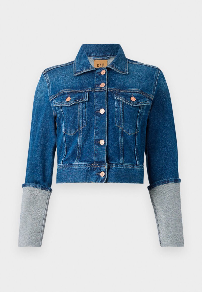 Abgeschnittene dunkelblaue Jeansjacke mit Kupferknöpfen, zwei Brusttaschen, Kragen und hellgrauen umgeschlagenen Ärmeln.