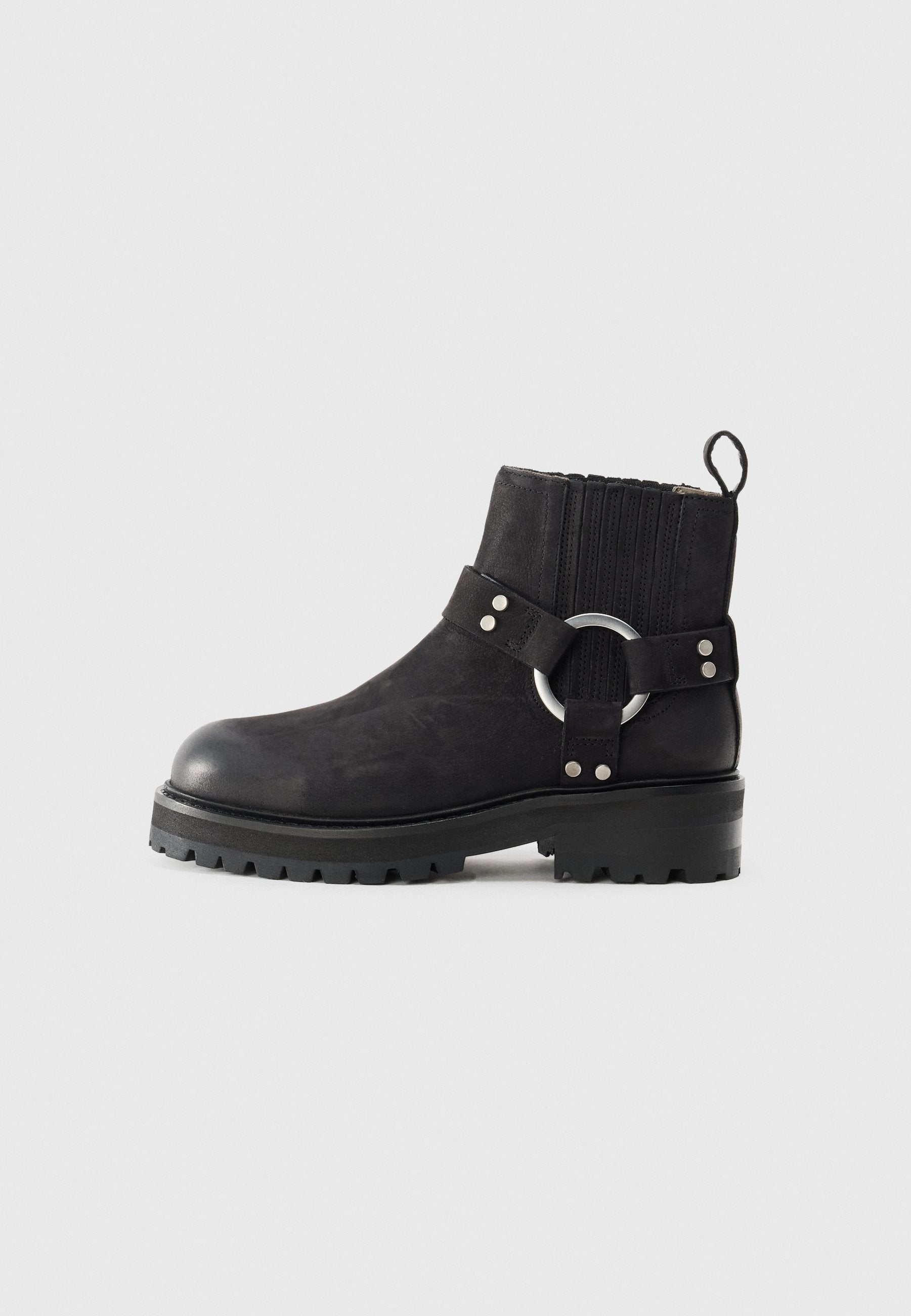 Schwarze Knöchelstiefel mit einer runden Zehenpartie, strukturiertem Obermaterial, elastischen Seiteneinsätzen und einem dekorativen silbernen Ringakzent. Grobprofilierte Sohle.