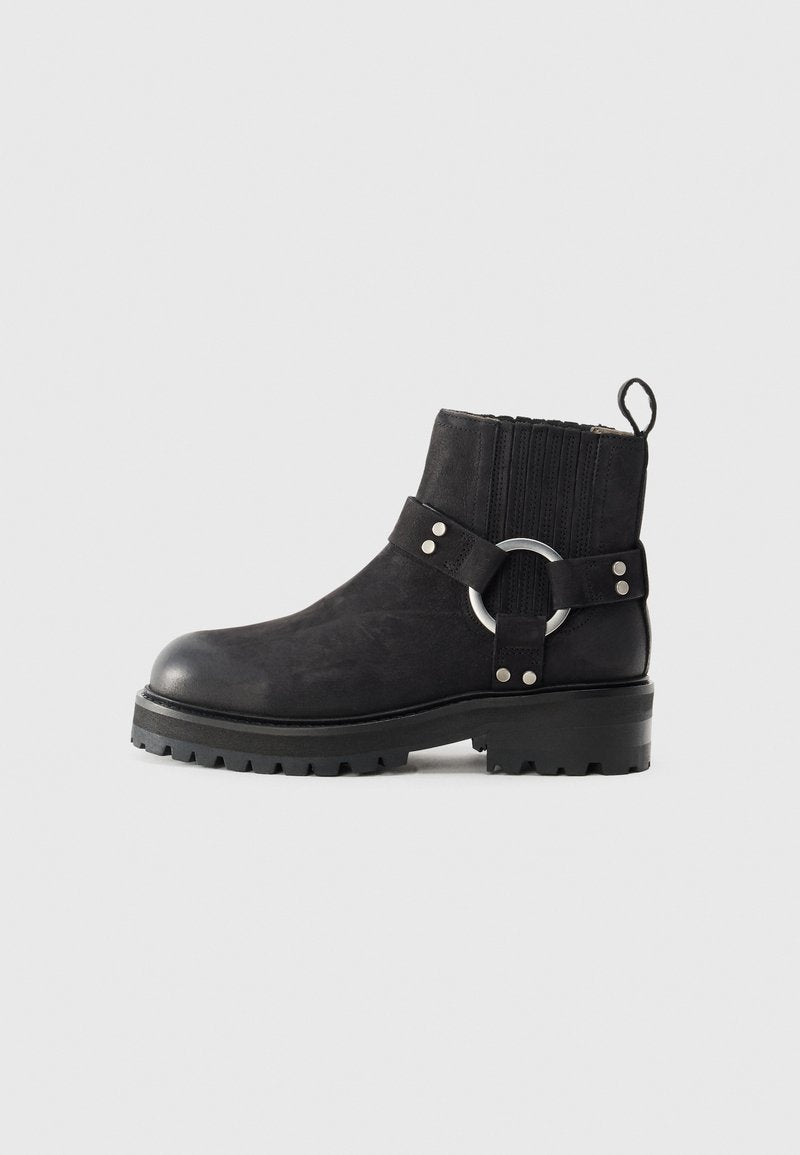 Schwarze Knöchelstiefel mit einer runden Zehenpartie, strukturiertem Obermaterial, elastischen Seiteneinsätzen und einem dekorativen silbernen Ringakzent. Grobprofilierte Sohle.