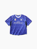 Blaues kurzärmeliges Sporttrikot mit weißem Kragen, schwarzen Seitenpartien, dem Schriftzug „awake ny“ und athletischen Aufnähern auf der Brust.