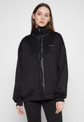 Schwarze Zip-Jacke mit hohem Kragen, verziert mit silbernen Nieten und einem Logo. Hergestellt aus glattem Stoff, mit lockerer Passform und langen Ärmeln.