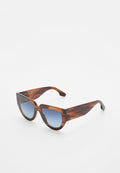 Schildpatt-Katzenaugen-Sonnenbrille mit blauen Verlaufslinsen, breiten Bügeln und eingeätztem Markennamen an der Seite.