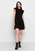 Schwarzes Kleid mit Rüschensleevs, gestuftem Rock und verstreuten metallischen Akzenten. Getragen mit schwarzen Plateau-Schuhen und knielangen Socken.