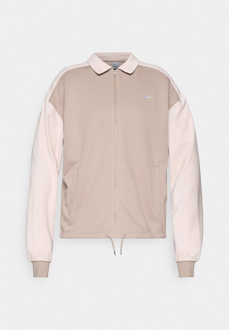 Beige Nike Zip-Up-Jacke mit hellpinkfarbenen Ärmeln, Kragen, elastischen Bündchen und Kordelzugsaum. Gesticktes Logo auf der Brust.