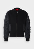 Schwarze Bomberjacke mit geripptem Strickkörper und glatten Nylonärmeln, Reißverschluss vorne und Seitentaschen. Figurbetonter Schnitt mit umgeschlagenen Saumen.