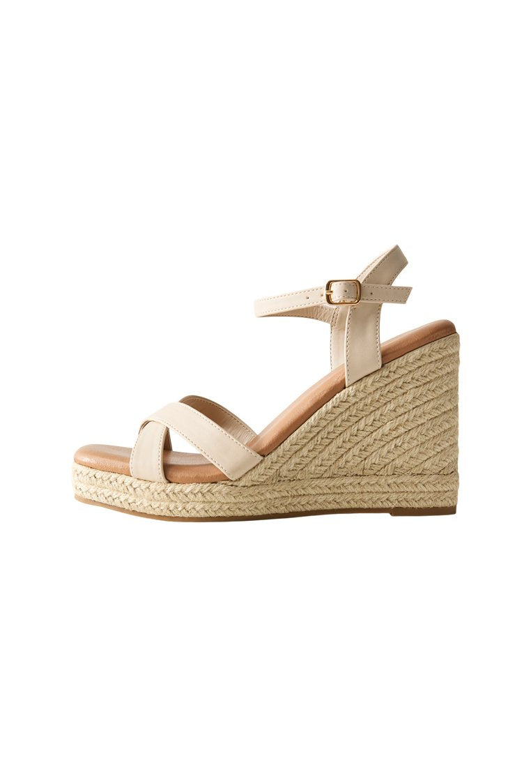 Beige Wedgesandalen mit überkreuzten Riemen, einer Schnalle am Knöchel und einer strukturierten Jute-Plattform. Glattes Leder-Obermaterial und gepolsterte Zunge.