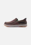 Brauner Mesh-Slipper mit grauer Sohle, grünem elastischem Seitenteil und Goodyear-Logo auf der Sohle, seitlich dargestellt.