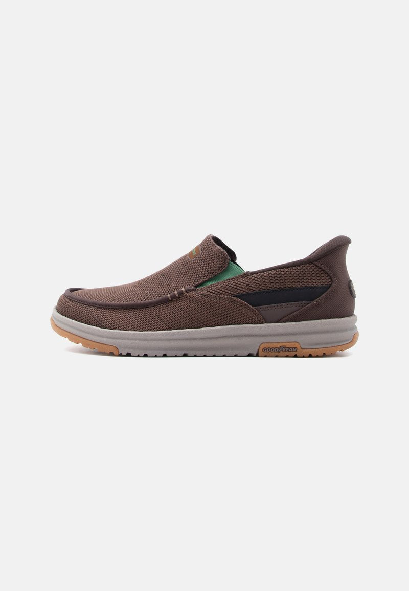 Brauner Mesh-Slipper mit grauer Sohle, grünem elastischem Seitenteil und Goodyear-Logo auf der Sohle, seitlich dargestellt.