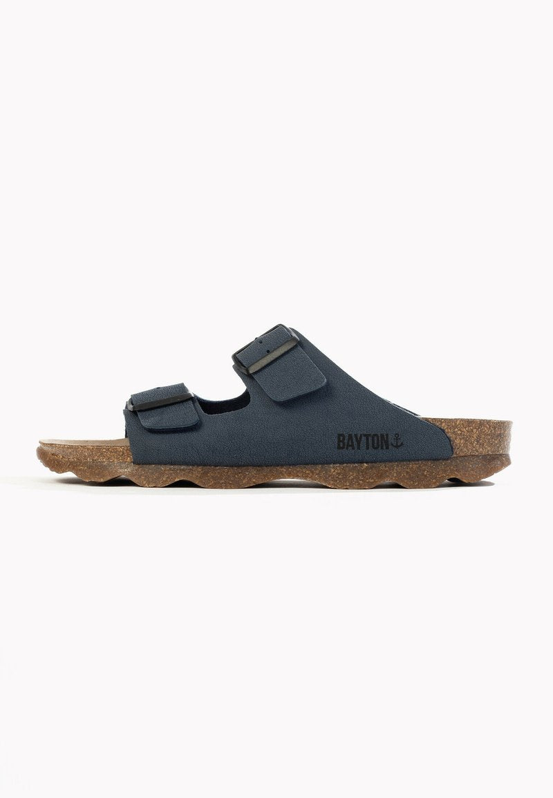Dunkelblaue Sandale aus strukturiertem Material mit zwei verstellbaren Riemen und einem braunen Korkfußbett. Die Sohle hat ein wellenförmiges Muster.
