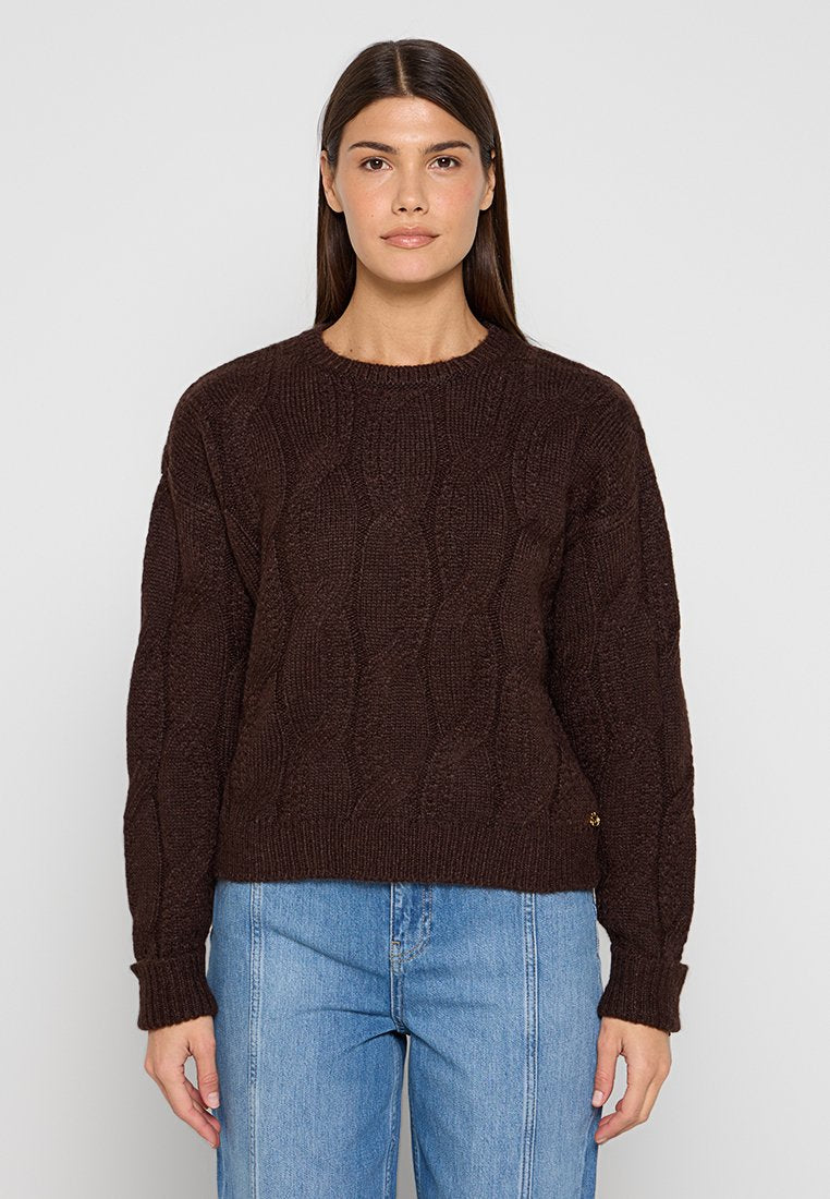 Brauner Strickpullover mit strukturiertem Muster, rundem Ausschnitt und gerippten Bündchen. Kombiniert mit hellblauen Jeans für einen Kontrast.