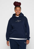 Marineblaue Kapuzenjacke mit strukturiertem Rippdesign, verstellbare Kapuze und gesticktem "Tommy Hilfiger"-Logo auf der Brust, kombiniert mit passenden Jogginghosen.