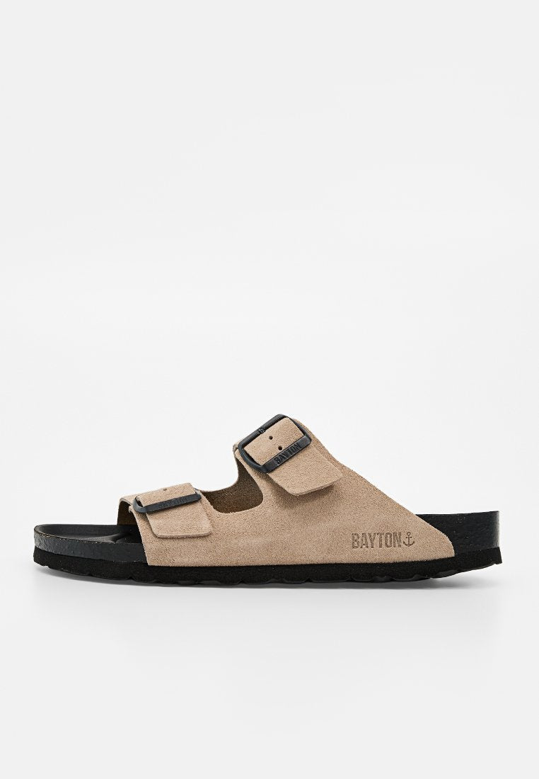 Beige Wildleder offene Sandale mit zwei verstellbaren schwarzen Schnallen und schwarzer Sohle, mit Bayton-Logo an der Seite.