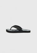 Schwarze Flip-Flops mit strukturiertem Schaumfußbett, dünnen Gummi-Riemen mit Nähdetails und kleinen Löchern in der Sohle zur Belüftung.
