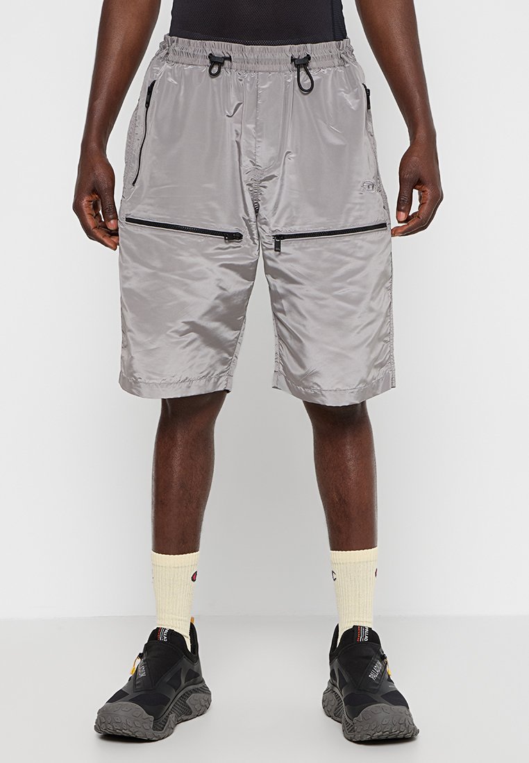 Graue, knielange Shorts aus leichtem Material. Verfügt über zwei seitliche Reißverschlusstaschen und einen elastischen Bund mit Kordelzug.
