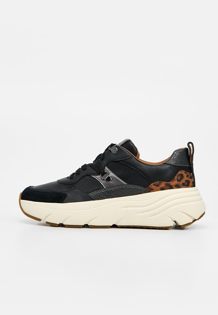 Schwarzer Sneaker mit dicker weißer Sohle, Schnürung vorne und braunem Leopardenmuster an der Ferse vor hellem, einfarbigem Hintergrund.