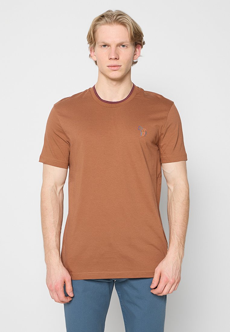 Braunes Baumwoll-T-Shirt mit Rundhalsausschnitt und kurzen Ärmeln, versehen mit einem kontrastierenden bordeauxroten Besatz und einem kleinen Motiv auf der linken Brust.