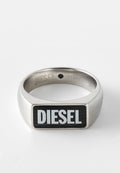 Edelstahlring mit rechteckigem schwarzem Emaille-Einlage, auf dem das Wort "DIESEL" in fetten weißen Buchstaben steht. Glatte Textur, polierte Oberfläche.