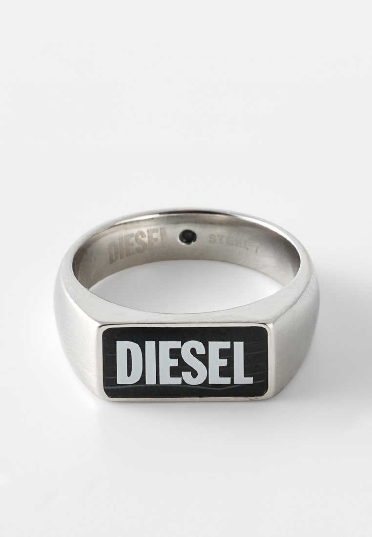 Edelstahlring mit rechteckigem schwarzem Emaille-Einlage, auf dem das Wort "DIESEL" in fetten weißen Buchstaben steht. Glatte Textur, polierte Oberfläche.