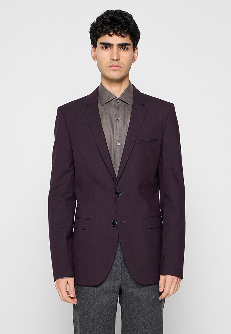 Dunkellila Blazer mit zwei Knöpfen, einfachen Kerbkragen und Seitentaschen, getragen über einem grauen Hemd. Glatter Stoff und taillierte Passform.