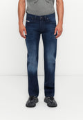 Mann in dunkelblauen lässigen Jeans, grauem T-Shirt und schwarzen Turnschuhen, der vor einem schlichten weißen Hintergrund steht.