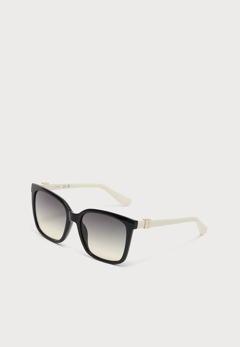 Schwarze quadratische Sonnenbrille mit verlaufend dunklen Gläsern und weißen Bügeln auf einem schlichten hellen Hintergrund.